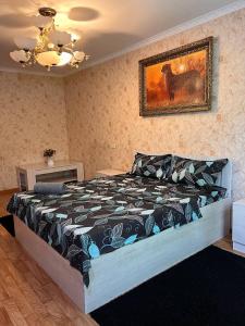 ein Bett in einem Schlafzimmer mit einem Bild an der Wand in der Unterkunft Апартаменты на Mege in Schymkent