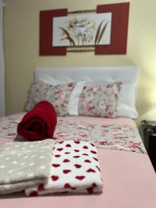 Una cama con toallas rojas y blancas. en Casa privativa completa e aconchegante! en São José
