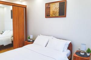 - une chambre avec un lit blanc et un miroir dans l'établissement River Site Lux Apartment, à Podgorica