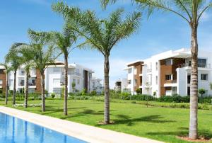 a row of palm trees in front of condos at Prestigia Golf city Bouskoura Apartment in Bouskoura