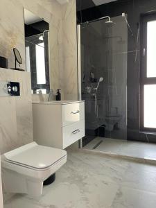 a white bathroom with a toilet and a shower at Shiba studio Mamaia in Mamaia