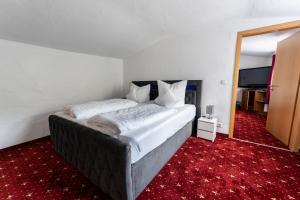 Schlafzimmer mit einem großen Bett und einem roten Teppich in der Unterkunft Hotel Haus Biggen in Attendorn
