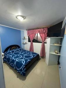 una camera con un letto blu e una finestra di Hermoso y acogedor departamento a Atuntaqui
