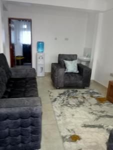 a living room with two chairs and a couch and a rug at Amalya suites . in Eldoret