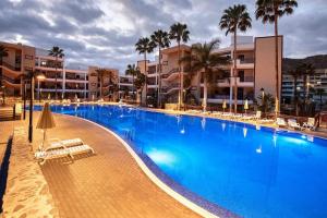 a large blue swimming pool with palm trees and buildings at Apartamento Balandros in Palm-mar