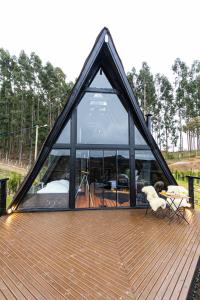 a frame house with a large window on a deck at Chalé do Canyon in Alfredo Wagner +29 photos
