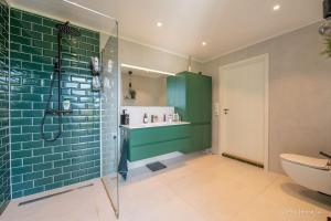 La salle de bains est pourvue d'une douche carrelée de couleur verte et de toilettes. dans l'établissement Henningsvær, Lofoten with fantastic view, à Henningsvær