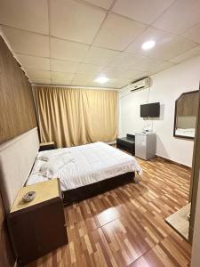 ein Schlafzimmer mit einem Bett und einem TV in der Unterkunft فندق الروان 