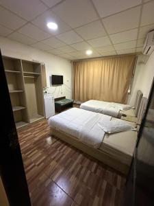 Cette chambre comprend deux lits et une télévision. dans l'établissement فندق الروان, 