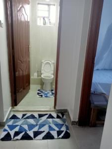 a bathroom with a toilet and a door with a rug at Amalya suites by TJ3 in Eldoret