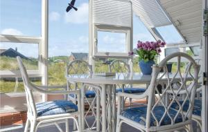 スナーヴィグにある3 Bedroom Nice Home In Ringkbingの白いテーブルと椅子、花の咲くポーチ