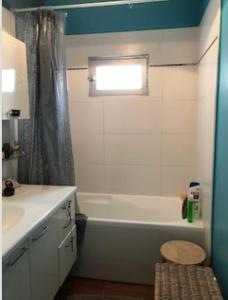 La salle de bains est pourvue d'une baignoire blanche, d'un lavabo et d'une fenêtre. dans l'établissement chambre au calme avec salle de bain privée, à Mérignac