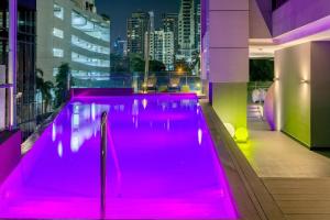 una piscina con iluminación rosa en un edificio en Aloft Panama en Panamá