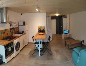 een keuken met een tafel in het midden van een kamer bij Logement avec terrasse Millau in Millau