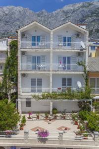 ein großes weißes Gebäude mit Balkonen und Blumen in der Unterkunft Villa Neda in Makarska