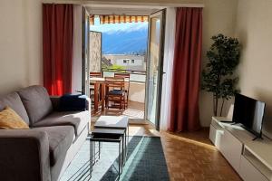 een woonkamer met een bank, een televisie en een balkon bij Apartment via San Carlo in Muralto-Locarno in Muralto