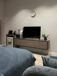 a living room with a television and a clock on the wall at سكون الفاخرة - دخول ذاتي in As Sayl aş Şaghīr