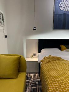 1 dormitorio con cama y sofá amarillo en سكون الفاخرة - دخول ذاتي en As Sayl aş Şaghīr