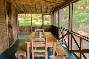 eine Veranda einer Hütte mit einem Holztisch und Stühlen in der Unterkunft Deer Hill Camp in Moultonborough