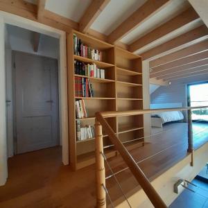 Habitación con techo de madera, estanterías y escalera. en Le gîte Pierre et Bois, en Houffalize