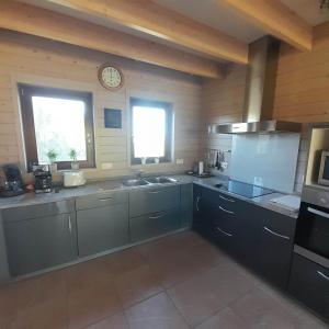 a kitchen with gray cabinets and a clock on the wall at Le gîte Pierre et Bois in Houffalize +16 photos