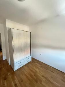 an empty room with a cabinet and a wooden floor at San snova apartmani Niš in Donja Vrežina