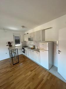 a kitchen with white appliances and a wooden floor at San snova apartmani Niš in Donja Vrežina