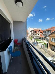 a balcony with a blue chair and a large window at San snova apartmani Niš in Donja Vrežina
