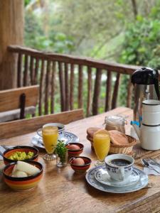 a wooden table with plates of food and cups of orange juice at Araplay Lodge in Santa Teresa