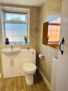 a bathroom with a toilet and a sink and a window at Willow Cottage - Billinge Wigan, sleeps 4 , parking and garden in Billinge