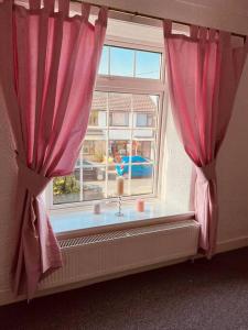 a window with pink curtains in a room at Willow Cottage - Billinge Wigan, sleeps 4 , parking and garden in Billinge