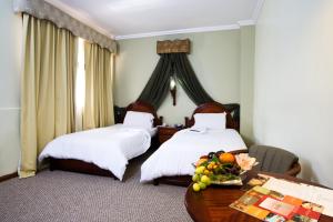 a hotel room with two beds and a table with fruit at Hotel Carvallo in Cuenca