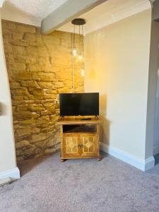 a room with a television on a stone wall at Willow Cottage - Billinge Wigan, sleeps 4 , parking and garden in Billinge