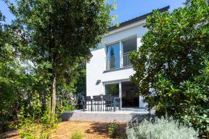 a white house with a patio and trees at Holiday house Bibi in Punat