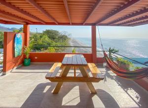 a picnic table and hammock on a balcony with the ocean at Malibu Rooftop in Nueva Gorgona