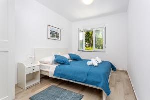 a white bedroom with a blue bed and a window at Holiday house Bibi in Punat