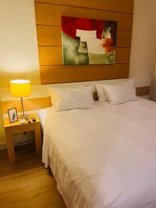 Un dormitorio con una gran cama blanca y una lámpara en Flat Congonhas, en São Paulo
