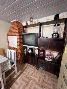 uma sala de estar com televisão e uma parede de tijolos em Casa privativa completa e aconchegante! em São José