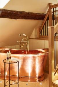 a copper tub in a bathroom with a staircase at Dawn at The Sun Inn Felmersham, Our Signature Duplex Suite in Sharnbrook