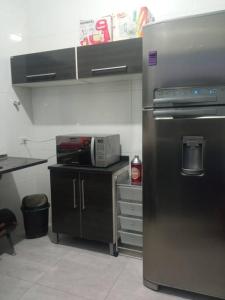 a kitchen with a stainless steel refrigerator and a microwave at Casa com piscina (Itanhaém) in Itanhaém