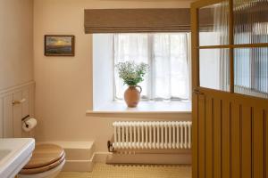 a bathroom with a toilet and a vase on a window at Dawn at The Sun Inn Felmersham, Our Signature Duplex Suite in Sharnbrook