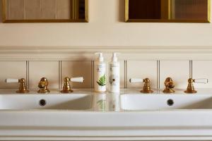 a bathroom with two white sinks with gold faucets at Dawn at The Sun Inn Felmersham, Our Signature Duplex Suite in Sharnbrook