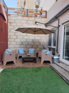 eine Terrasse mit einem Tisch, Stühlen und einem Sonnenschirm in der Unterkunft Stylish Apartment with garden in Kairo