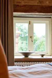 a bedroom with a window with two bowls on a window sill at Dawn at The Sun Inn Felmersham, Our Signature Duplex Suite in Sharnbrook