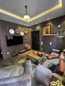 ein Wohnzimmer mit Sofas, einem Tisch und einem TV in der Unterkunft Stylish Apartment with garden in Kairo