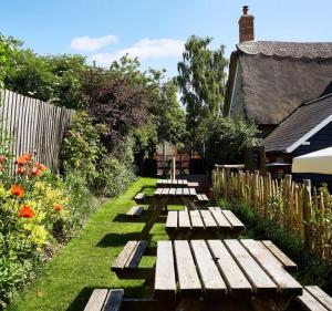 a row of wooden benches in a garden at Dawn at The Sun Inn Felmersham, Our Signature Duplex Suite in Sharnbrook