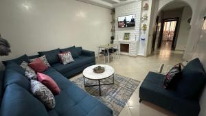 - un salon avec un canapé bleu et une table dans l'établissement APPARTEMENT COSY Au PALMERAIE VILLAGE - 5 PISCINES, à Marrakech