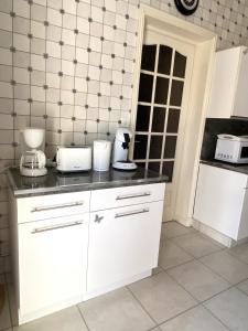 a kitchen with white cabinets and black counter tops at Maison au calme, 6 voyageurs in Riorges