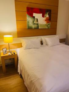 聖保羅的住宿－Flat Congonhas，卧室配有白色大床和灯