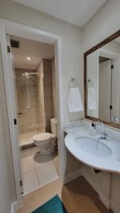 y baño con lavabo, aseo y espejo. en Apê em Itaipava, en Petrópolis